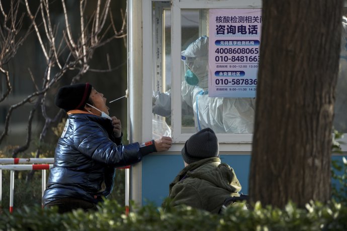 Pracovník v ochrannom odeve testuje miestneho obyvateľa na ochorenie covid-19 v Pekingu. Foto - TASR/AP