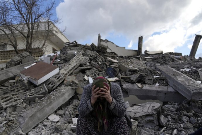 Žena sedí na ruinách, pod ktorými záchranári hľadajú nezvestné osoby po zemetrasení v Turecku. Foto - TASR/AP