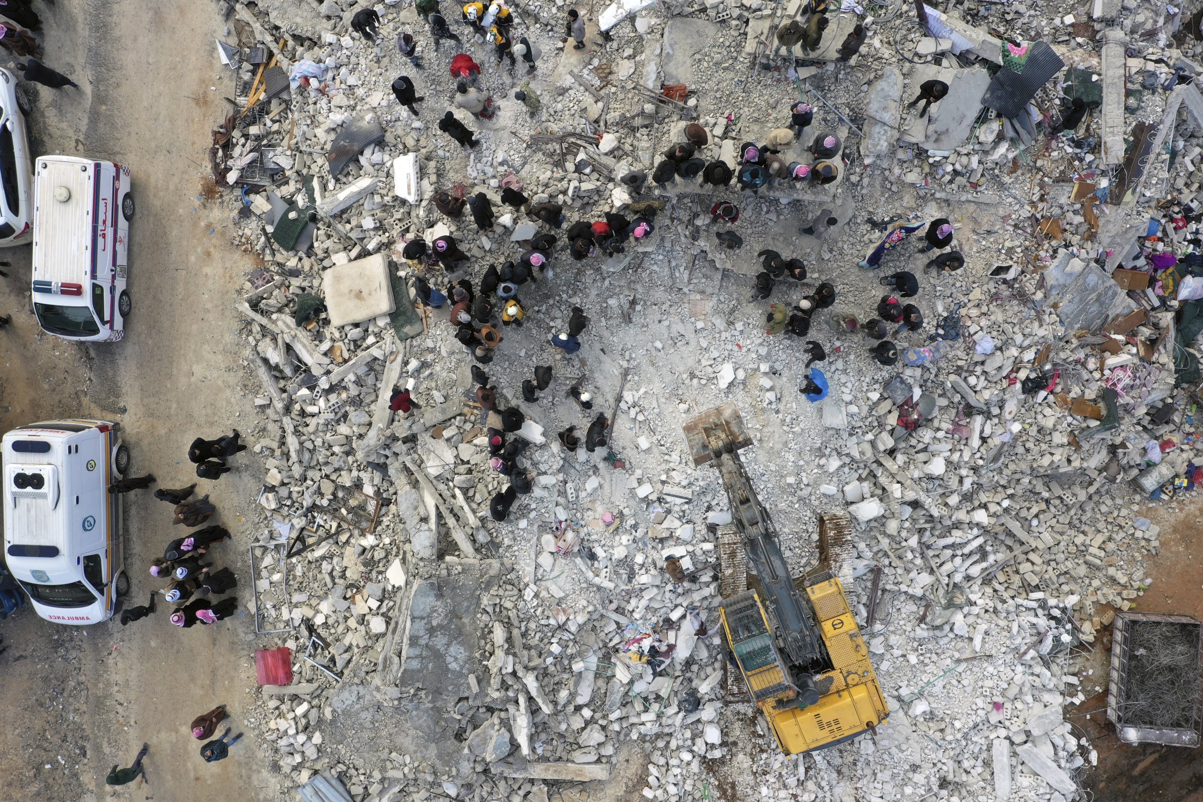 Záchranári a obyvatelia prehľadávajú sutiny zrútenej budovy v sýrskom Hareme neďaleko tureckej hranice. Foto - TASR/AP