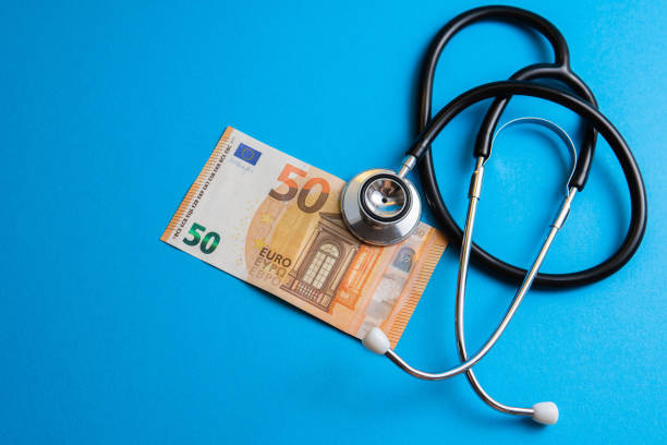 Closeup shot of a fifty euro banknote and a stethoscope on blue background. Concept of health care and community medicine price.