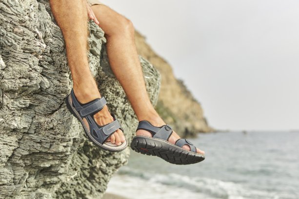 Pánske nohy v sandáloch Rieker pri mori