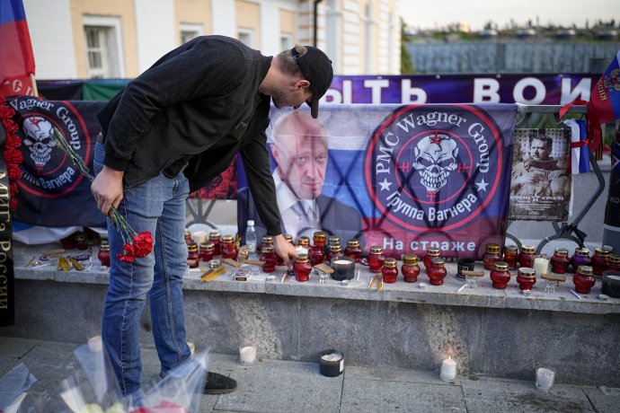 Muž v Moskve kladie sviečku k pouličnému pamätníku Jevgenija Prigožina a ďalších vagnerovcov. Foto - TASR/AP