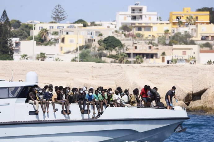 Migranti sedia na palube plavidla talianskej pobrežnej stráže, ktoré ich po záchrane na mori preváža na taliansky ostrov Lampedusa v piatok 15. septembra 2023. Foto -TASR/AP