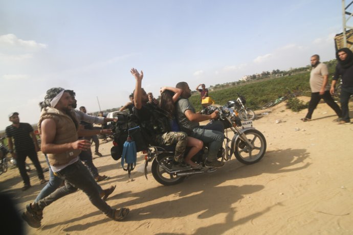 Militanti z hnutia Hamas odvážajú na motorke rukojemníčku z Izraela. Foto - TASR/AP