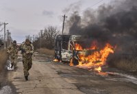 Ukrajinskí vojaci pri Bachmute idú okolo autobusu, ktorí zničil ruský dron. Foto - TASR/AP