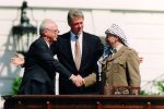 Israeli Prime Minister Yitzhak Rabin (left) and Palestine Liberation Organization Chairman Yasser Arafat (right) shake hands at the White House in front of President Bill Clinton in September 1993. The new play OSLO is a dramatization of events that led to a historic agreement. David Ake/AFP/Getty Images
