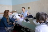 Karolína, ktorá je na posteli s dcérou Natálkou, sa zhovára s nemocničnou kaplánkou Doubravkou Vokáčovou. Foto Deník N - Ludvík Hradilek